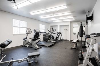 A spacious gym with a variety of equipment including treadmills, stationary bikes, and weight machines